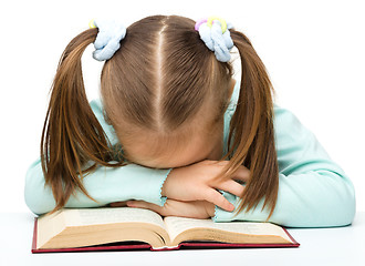 Image showing Cute little girl is sleeping on a book