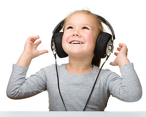 Image showing Cute little girl enjoying music using headphones