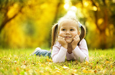 Image showing Cute little girl is playing with leaves in park