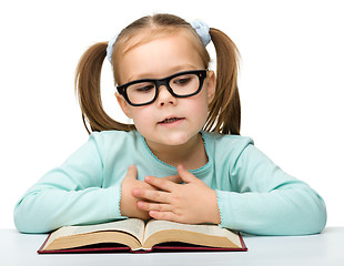 Image showing Cute little girl reads a book wearing glasses