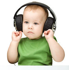 Image showing Cute little boy enjoying music using headphones