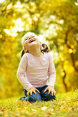 Image showing Cute little girl is playing with leaves in park