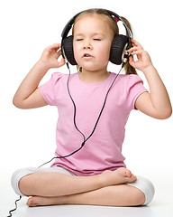 Image showing Cute little girl enjoying music using headphones