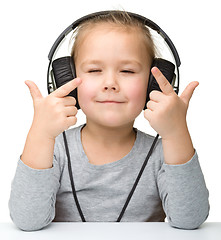 Image showing Cute little girl enjoying music using headphones