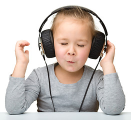 Image showing Cute little girl enjoying music using headphones