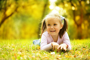 Image showing Cute little girl is playing with leaves in park
