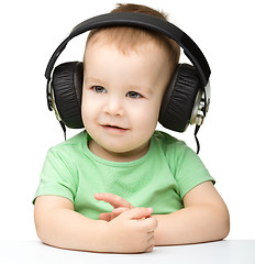 Image showing Cute little boy enjoying music using headphones