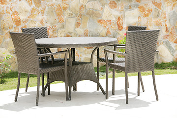 Image showing Table and chairs in a tropical garden with a stone wall texture