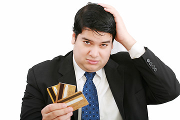 Image showing Upset robbed man glaring at his many credit cards.