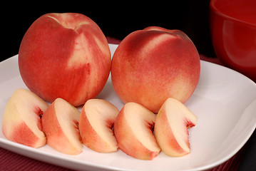 Image showing Whole and sliced white peaches on a white plate