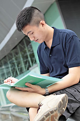 Image showing casual asian businessman texting on his book. 