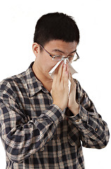 Image showing Young man with a cold blowing nose on tissue 