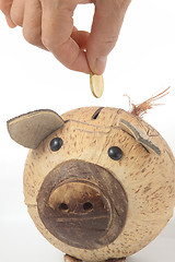 Image showing Saving, male hand putting a coin into piggy bank. 