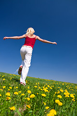 Image showing young woman in red outfit having fun on meadow