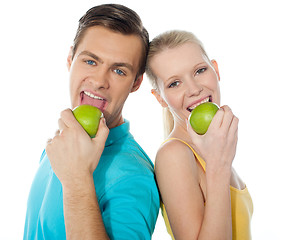 Image showing Young couple posing back to back with green apples