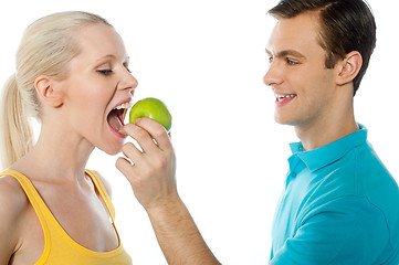 Image showing Young guy making her girlfriend eat an apple