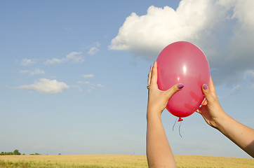 Image showing Woman hand hold red balloon background sky field 