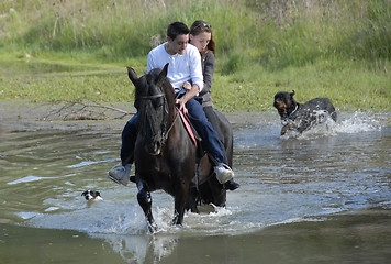 Image showing riding couple in a river with dogs