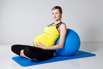 Image showing Pregnant woman relaxing against fitness ball