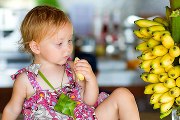 Image showing Outdoor portrait of toddler girl with bananas