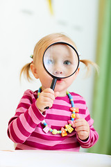 Image showing Toddler girl looking through magnifier