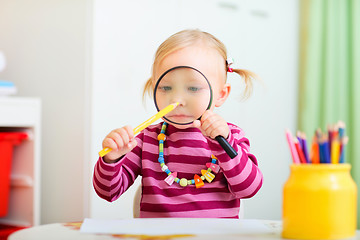 Image showing Funny toddler girl playing with magnifier