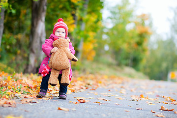 Image showing Toddler girl with teddy bear outdoors on autumn day