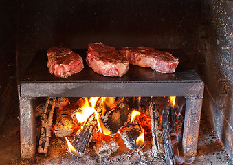 Image showing pork steaks preparing on the on a stone plate