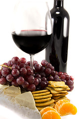 Image showing Bottle of red wine with some grapes