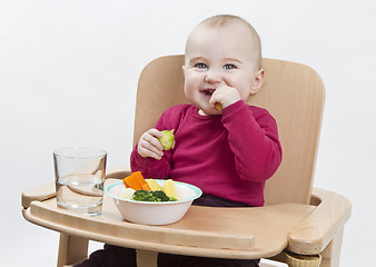 Image showing young child eating in high chair