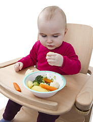 Image showing young child eating in high chair