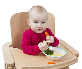 Image showing young child eating in high chair