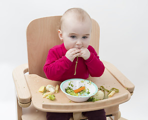 Image showing young child eating in high chair