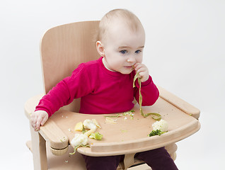 Image showing young child eating in high chair