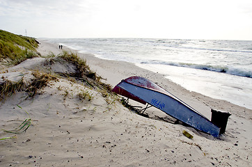 Image showing rusty boat lie on sea sand dunes beach people walk 