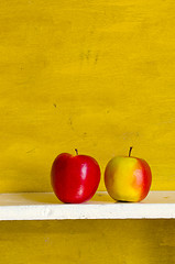 Image showing Apples on white shelve yellow wall background. 