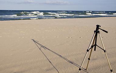 Image showing Camera tripod standing in the seasand. 