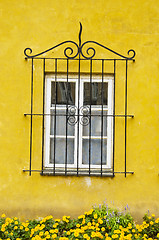 Image showing House window with a decorative protective grating. Yellow wall. 