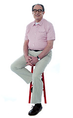 Image showing Confident senior man resting on stool