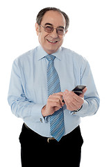 Image showing Smiling elder business executive texting