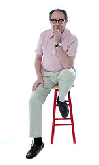 Image showing Confident senior man resting on stool