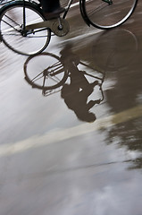 Image showing Man on bicycle in puddle reflection