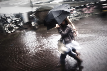 Image showing Two women under umbrella in rain and wind