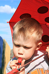 Image showing small boy under red umbrella