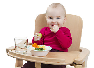 Image showing young child eating in high chair