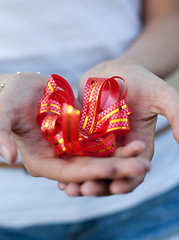 Image showing young woman holds a gift bow in hands