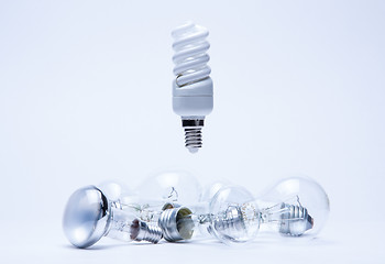 Image showing energy saving light hanging over incandescent