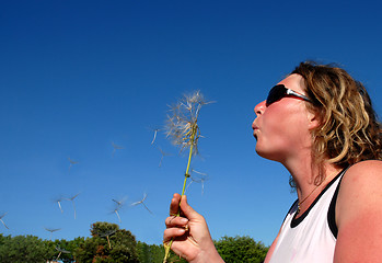 Image showing Young woman blowing a dandelion