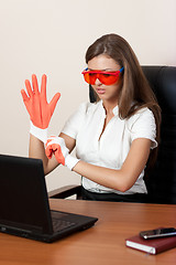 Image showing young woman behind table with laptop in gloves