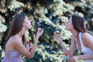 Image showing Two young women make soap bubbles